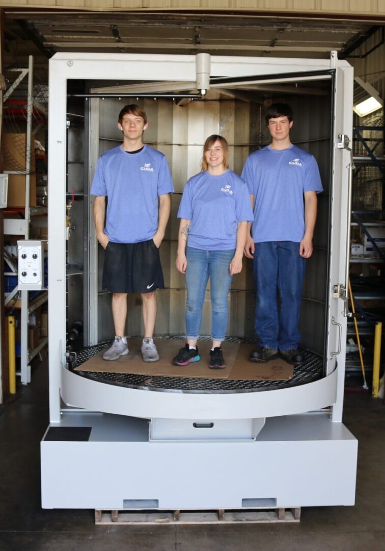 Three people standing in a large machine